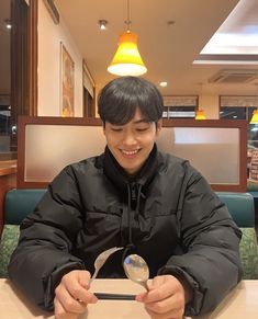 a man sitting at a table with spoons in front of him