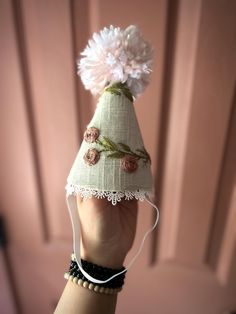 a hand is holding a small hat with flowers on it