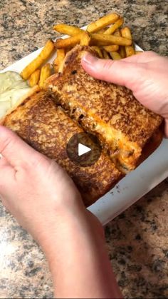 a person holding a grilled cheese sandwich with french fries in front of them on a plate