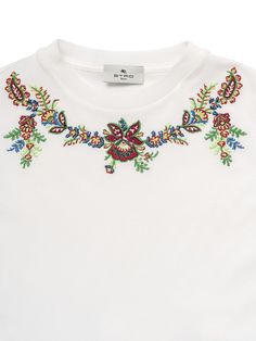 a white t - shirt with colorful embroidered flowers on the chest and collar, front view