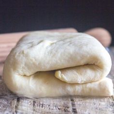 two uncooked pizza doughs stacked on top of each other next to rolling pins