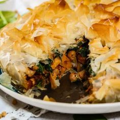 a close up of a casserole on a plate with broccoli in the background