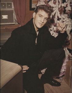 a man sitting in front of a christmas tree