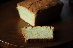 a loaf of bread sitting on top of a wooden plate next to a slice of cake