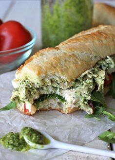 a sandwich cut in half sitting on top of a piece of paper next to a bowl of tomatoes