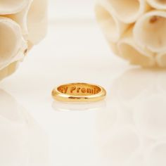 a close up of a gold ring on a white surface with flowers in the background