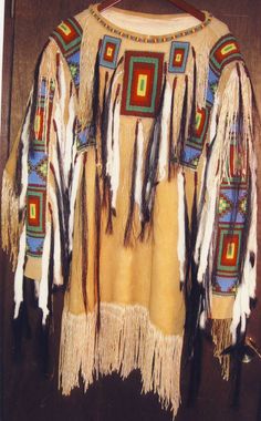 an old native american jacket with feathers on it's chest and fringes around the shoulders