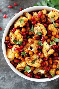 a bowl filled with cauliflower and pomegranate on top of a table