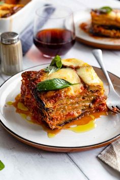 a white plate topped with lasagna covered in sauce