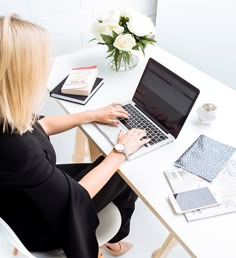 a woman sitting at a desk using a laptop computer