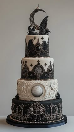 a three tiered cake decorated with black and white icing, topped with an intricate design