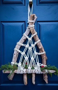 a christmas tree made out of driftwood and rope hanging on a blue front door