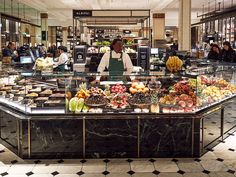 a woman standing in front of a counter filled with food