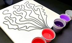 the paint is being used to create an art project on paper with colored cups next to it