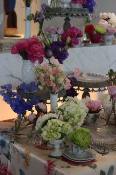 a table topped with lots of different types of flowers on top of a cake stand