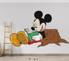 a mickey mouse reading a book while leaning on a tree stump wall decal in a children's room