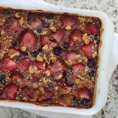 a casserole dish with strawberries and nuts in it sitting on a table