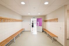 a woman is standing in the doorway of a public restroom with benches on either side