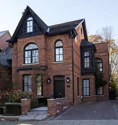 a large brick house with two story windows and black trim on the front entrance door