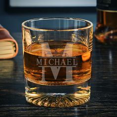 a personalized whiskey glass sits on a table next to two books and a book