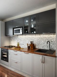 a kitchen with gray cabinets and wood floors