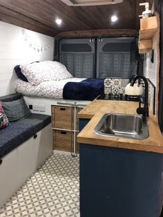 a kitchen with a sink, counter and bed inside of the campervane