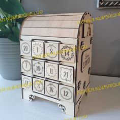 a wooden clock with numbers on it sitting next to a potted plant in a room