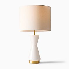 a white table lamp with a gold base and a light shade on it's side