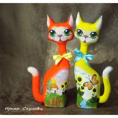 two colorful cat figurines sitting next to each other on a brown tablecloth