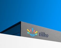 a sign on the side of a building that says tilko against a blue sky