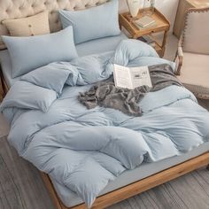 a bed with blue comforters and pillows on top of it in a room next to a chair