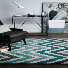 a living room area with a chair, table and rug on the floor in front of it