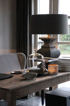 a wooden table with a lamp on top of it next to a chair and window