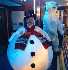 a woman standing next to a giant snowman and polar bear