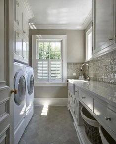 a laundry room with washer and dryer in the corner, cabinets on both sides