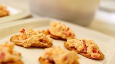 small crackers are arranged on a white plate next to a glass of milk in the background