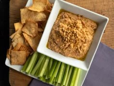 celery sticks and chips on a table with dip in a bowl next to them