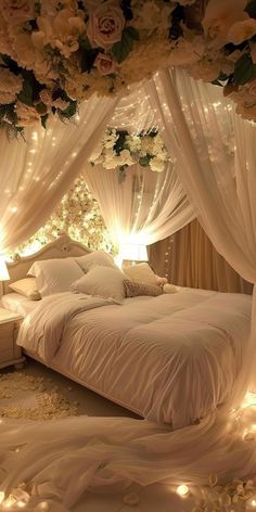 a bed with white sheets and lights on the headboard is surrounded by flowers, petals and drapes