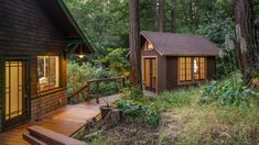 a small cabin in the woods with stairs leading up to it's front door