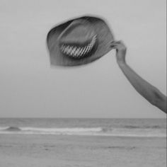 a black and white photo of a person throwing a frisbee at the beach