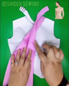 someone cutting out an origami dress with pink ribbon