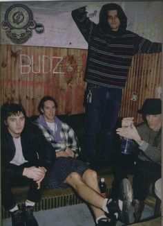 three men sitting on a couch in front of a wooden wall with the word buzz written on it