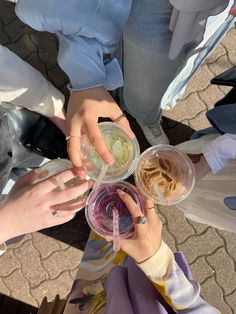 several people are holding cups with food in them and one person is reaching for something