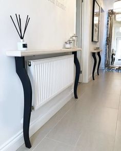 a white and black console table sitting next to a wall with mirrors on the walls