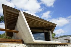 a house made out of concrete sitting on top of a rock wall next to a palm tree