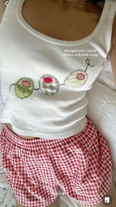 a woman laying on top of a bed wearing red and white checkered shorts with buttons