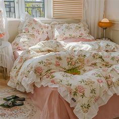 a bed with pink and white flowers on it next to a window in a bedroom