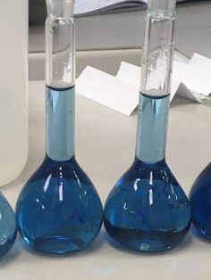 three blue flasks filled with liquid sitting on a table