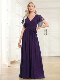 a woman in a long purple dress posing for the camera with her hands on her hips