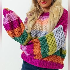 a woman with blonde hair wearing a multicolored knitted sweater and holding her hand on her hip